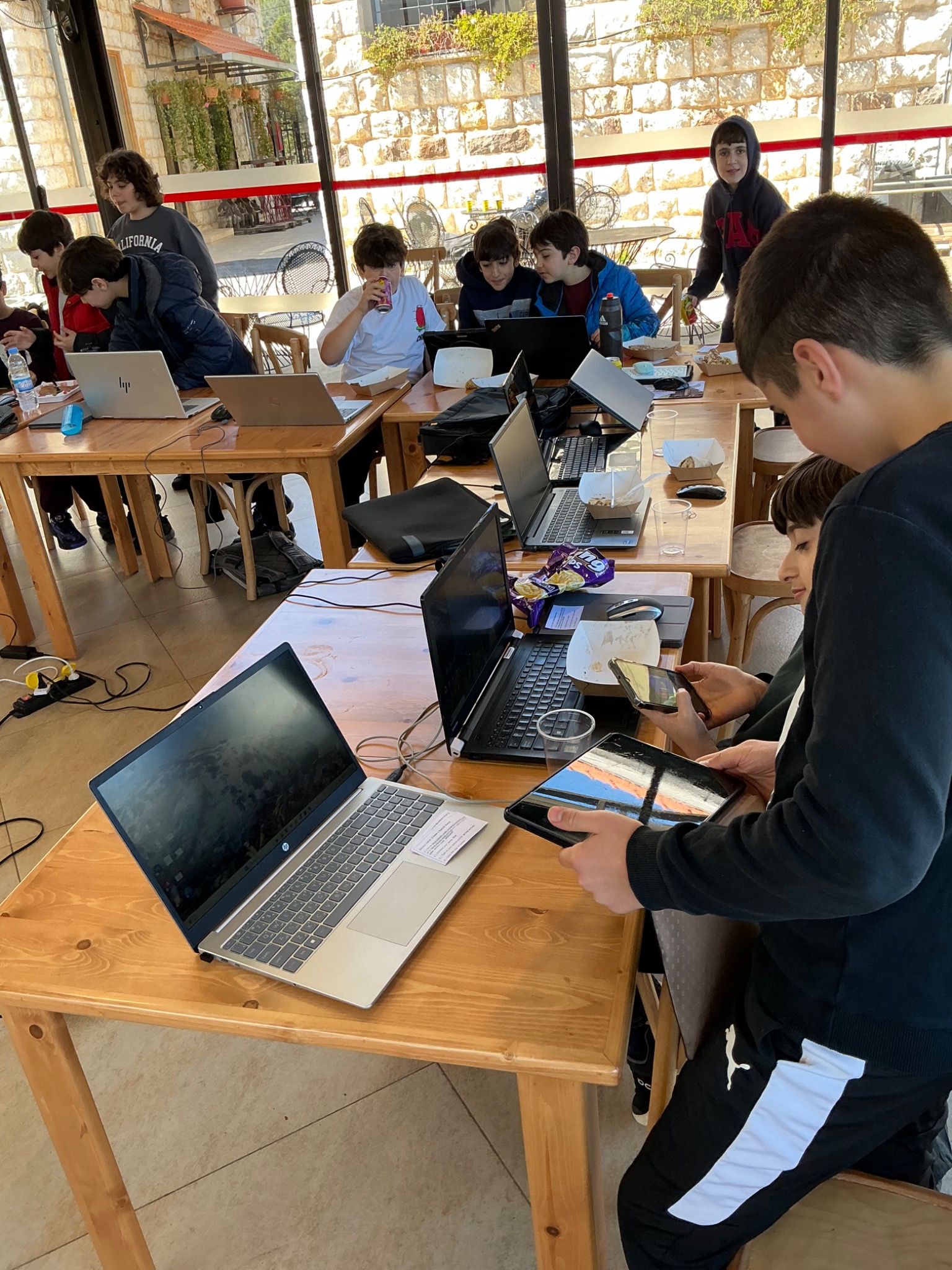 Students working together with laptops and tablets at a coding workshop
